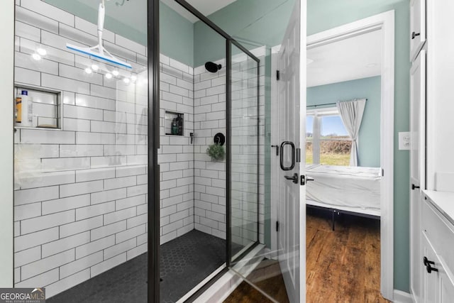 ensuite bathroom featuring a shower stall, ensuite bath, and wood finished floors