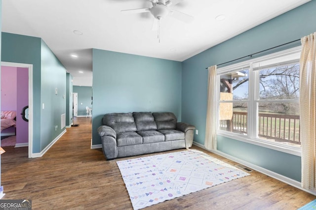 living area with a ceiling fan, visible vents, wood finished floors, and baseboards