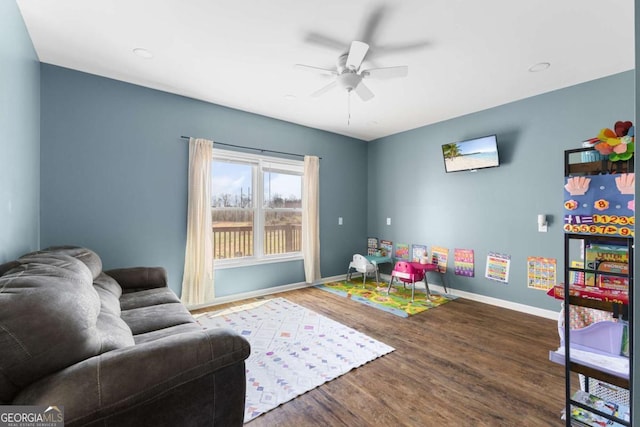 recreation room with a ceiling fan, wood finished floors, and baseboards