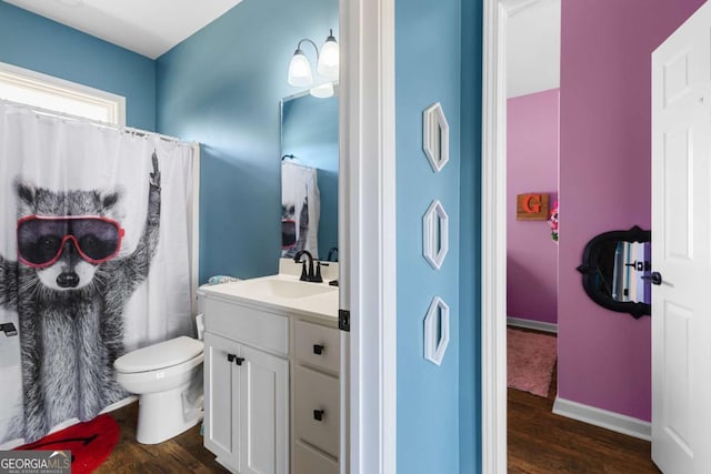 full bath featuring toilet, vanity, baseboards, and wood finished floors