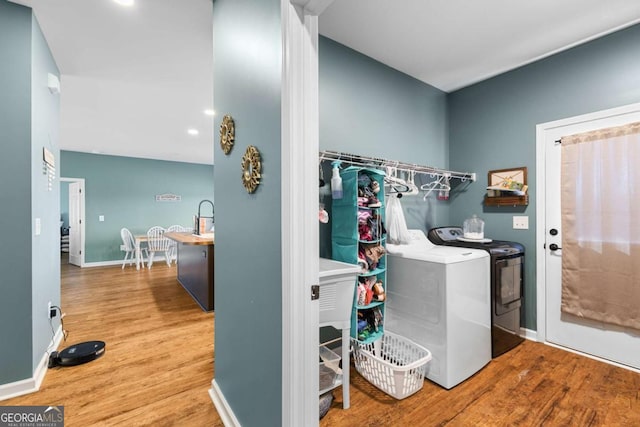 washroom featuring laundry area, wood finished floors, baseboards, and washing machine and clothes dryer