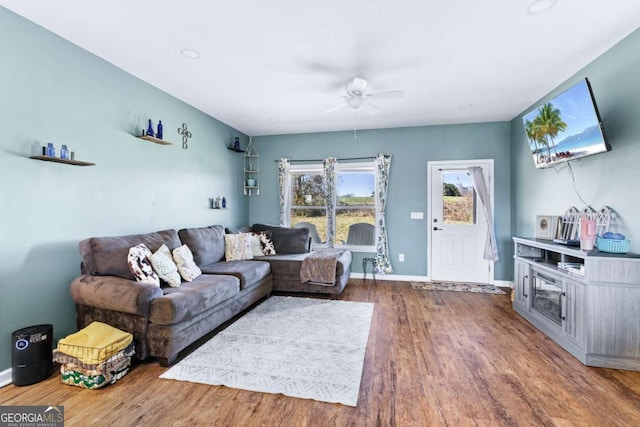 living room with ceiling fan, baseboards, and wood finished floors