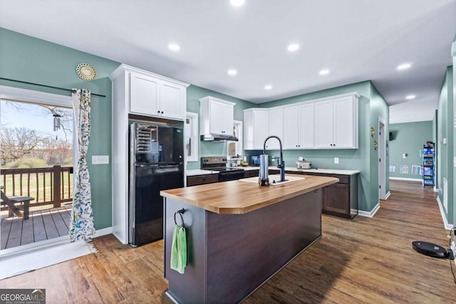 kitchen featuring wood counters, dark wood-style floors, stainless steel range with electric cooktop, freestanding refrigerator, and white cabinets