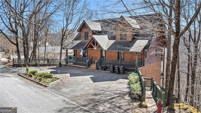 view of front of property featuring covered porch, driveway, and a shingled roof