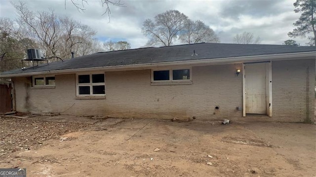 back of house with brick siding and cooling unit