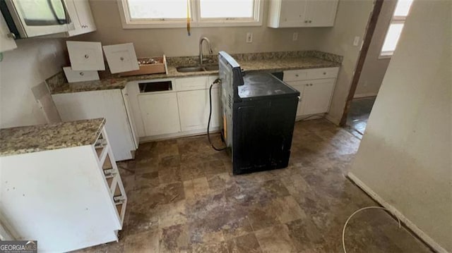 kitchen featuring stainless steel microwave, a healthy amount of sunlight, white cabinetry, and a sink