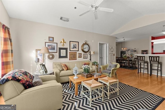 living area featuring vaulted ceiling, visible vents, a ceiling fan, and wood finished floors