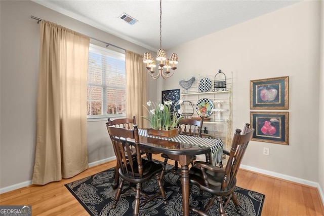 dining space with a chandelier, visible vents, baseboards, and wood finished floors