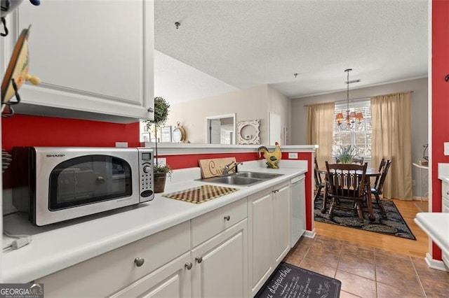 kitchen featuring stainless steel microwave, dishwasher, light tile patterned flooring, white cabinets, and a textured ceiling