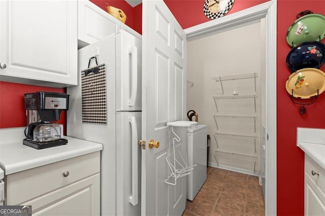 kitchen with tile patterned flooring, light countertops, white cabinets, and freestanding refrigerator