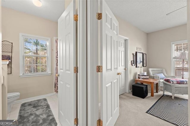 office featuring light tile patterned floors, light colored carpet, baseboards, and a textured ceiling