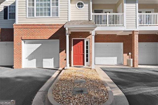 doorway to property featuring a garage and brick siding