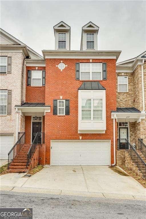 townhome / multi-family property with a garage, brick siding, and driveway