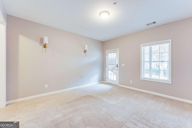 carpeted spare room featuring visible vents and baseboards