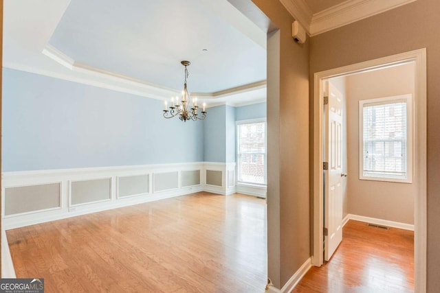 interior space with light wood finished floors, visible vents, crown molding, a tray ceiling, and a notable chandelier