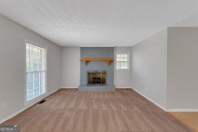 unfurnished living room with visible vents, carpet, baseboards, a fireplace, and a textured ceiling