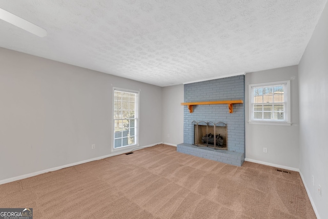 unfurnished living room featuring visible vents, a brick fireplace, baseboards, carpet flooring, and a textured ceiling