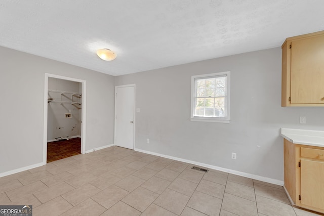 unfurnished dining area with light tile patterned floors, visible vents, baseboards, and a textured ceiling