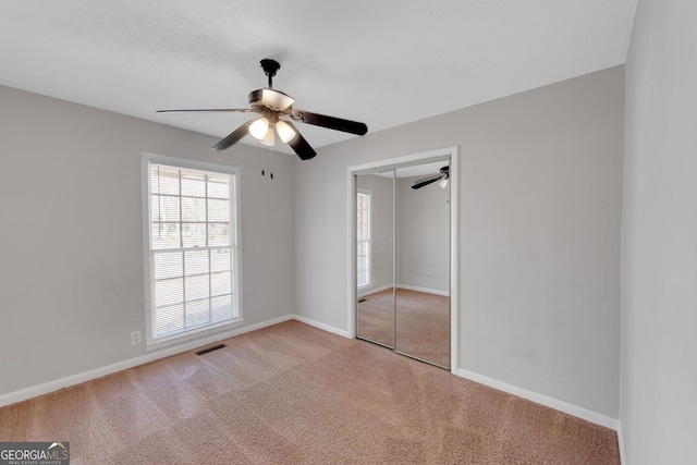 unfurnished bedroom with carpet flooring, baseboards, visible vents, and a closet