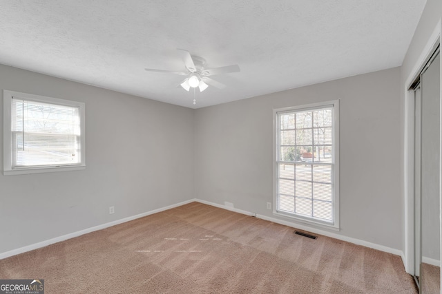 unfurnished bedroom with visible vents, a textured ceiling, a closet, carpet, and baseboards