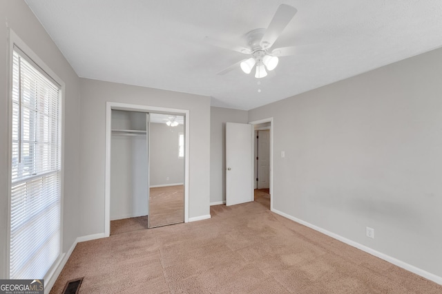 unfurnished bedroom with light carpet, visible vents, a closet, and baseboards