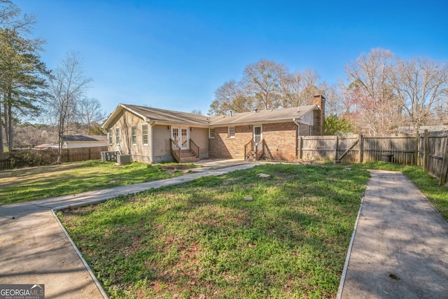 rear view of house with entry steps, a yard, a fenced backyard, and a chimney