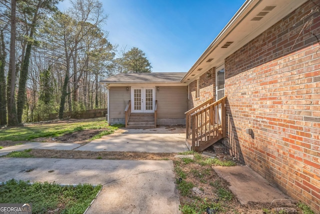 property entrance featuring brick siding, crawl space, and french doors