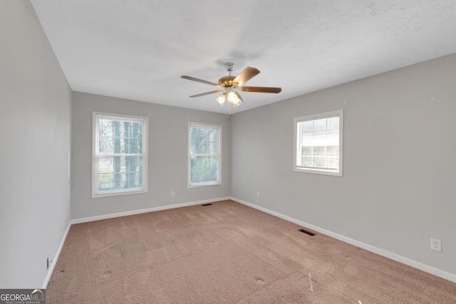 unfurnished room featuring carpet flooring, a healthy amount of sunlight, visible vents, and baseboards