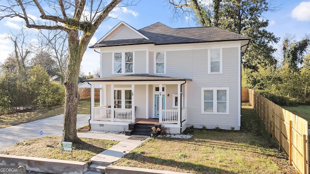 traditional style home featuring a porch, a shingled roof, a front yard, and fence