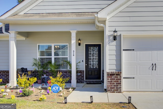 516 Grand Magnolia St, Jackson, GA 30233 - doorway to property with an attached garage, brick siding, and covered porch