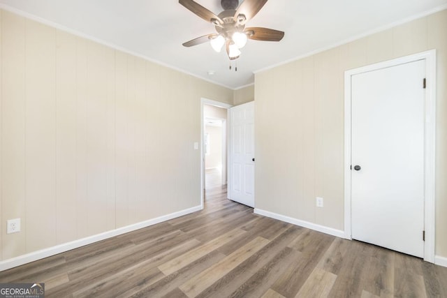 unfurnished bedroom featuring ceiling fan, wood finished floors, baseboards, and ornamental molding