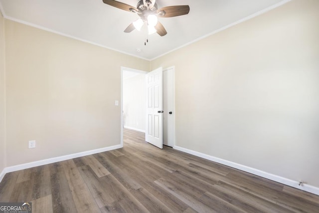 empty room with a ceiling fan, crown molding, baseboards, and wood finished floors