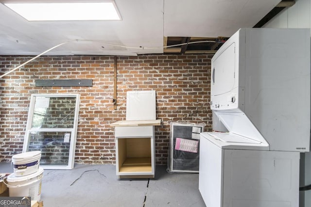 interior space with stacked washer / dryer and brick wall