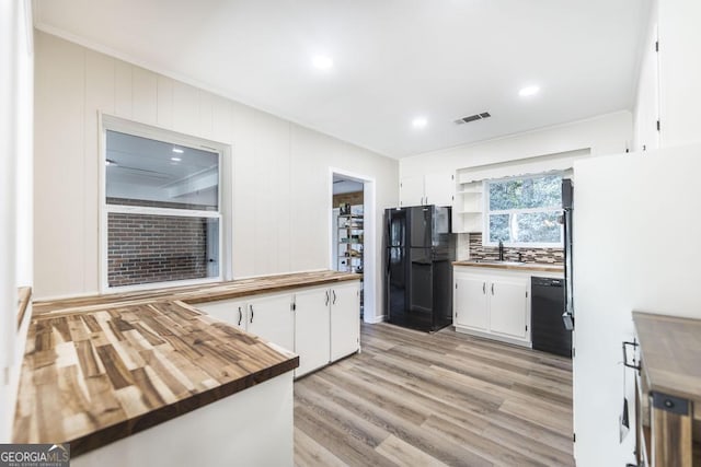 kitchen featuring white cabinetry, black appliances, visible vents, and wooden counters