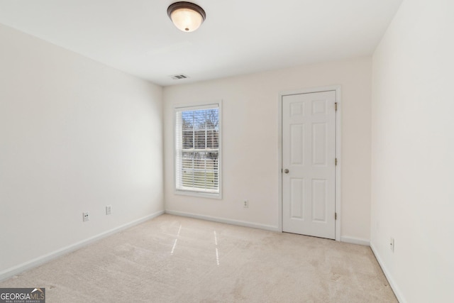 carpeted spare room featuring visible vents and baseboards