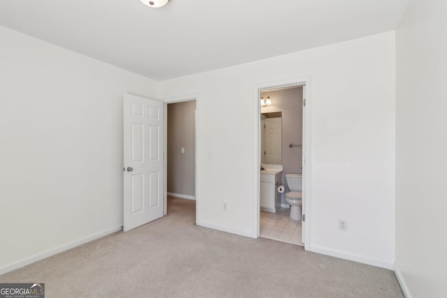 unfurnished bedroom with connected bathroom, baseboards, and carpet