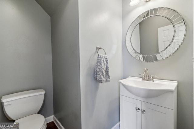 half bath with vanity, toilet, and baseboards