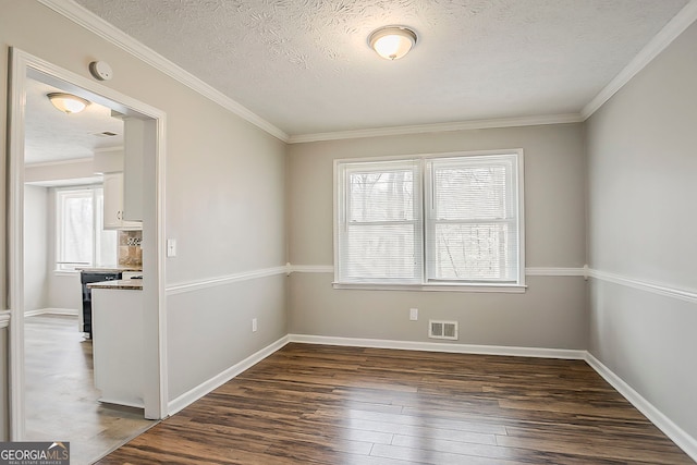 empty room with baseboards, visible vents, dark wood-style flooring, a textured ceiling, and crown molding