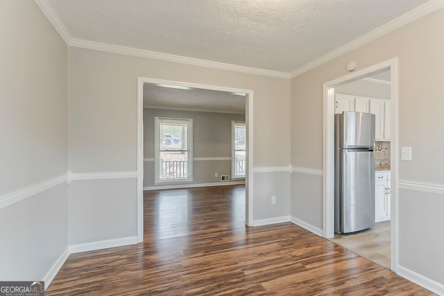 unfurnished room featuring crown molding, wood finished floors, baseboards, and a textured ceiling