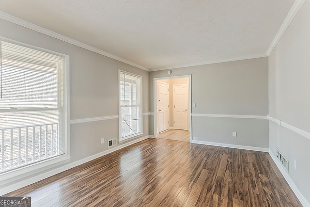 empty room featuring dark wood-style floors, visible vents, and a healthy amount of sunlight