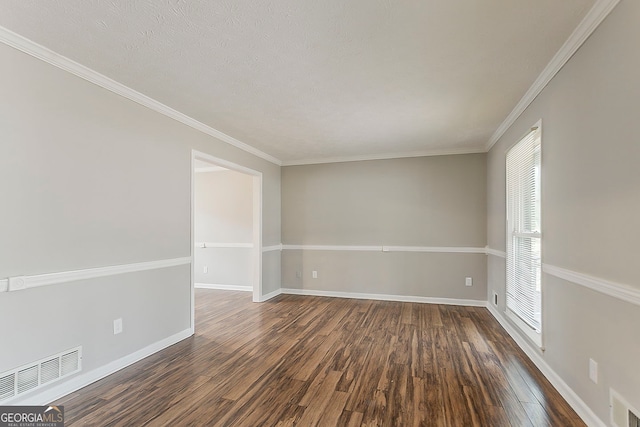 empty room with visible vents, baseboards, dark wood finished floors, and ornamental molding