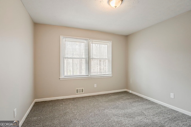 carpeted spare room with visible vents and baseboards