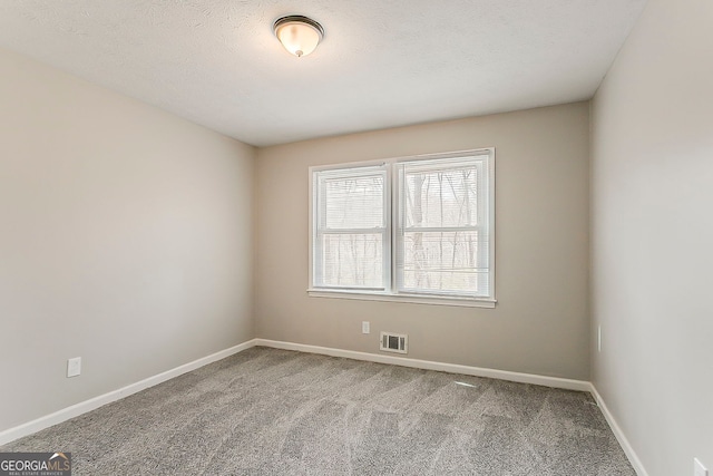 unfurnished room with carpet flooring, visible vents, baseboards, and a textured ceiling