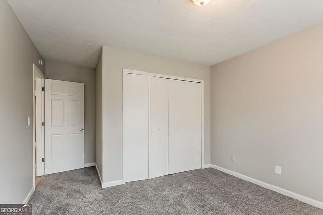 unfurnished bedroom featuring a closet, baseboards, carpet, and a textured ceiling