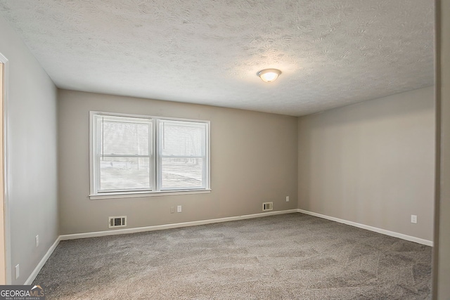 carpeted spare room with visible vents, baseboards, and a textured ceiling