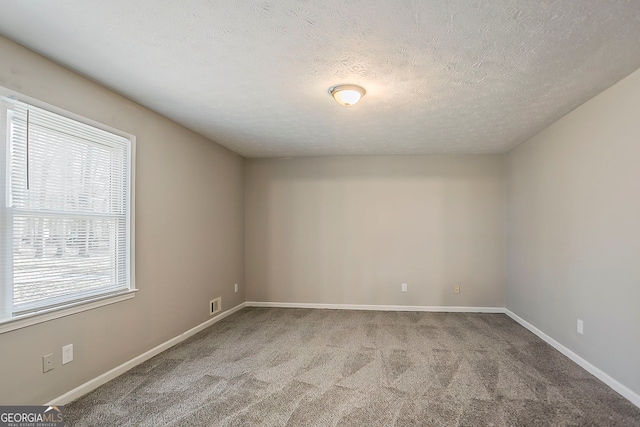 unfurnished room featuring visible vents, a textured ceiling, baseboards, and carpet