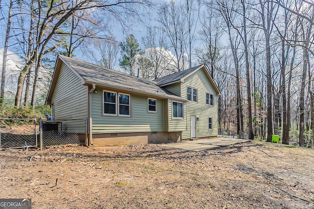 back of house featuring crawl space, a gate, and fence