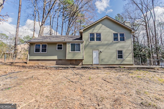 back of property with crawl space, a wooden deck, a chimney, and fence