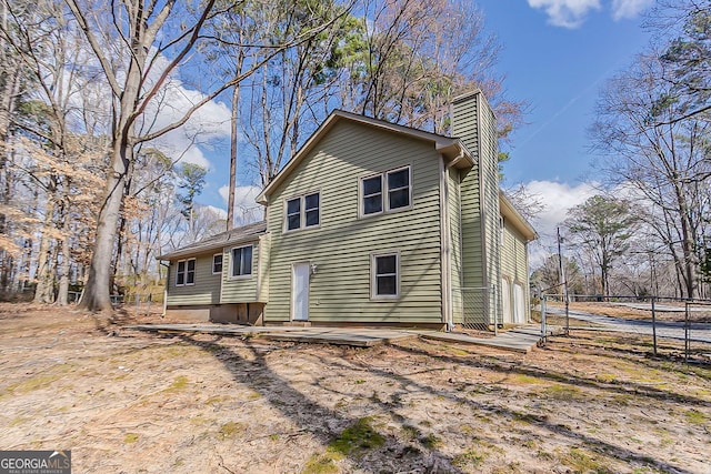 back of property with fence and a chimney