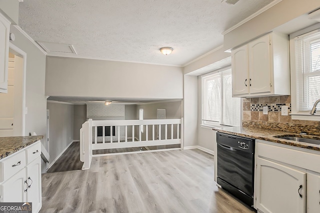 kitchen with dark stone countertops, light wood finished floors, a sink, white cabinets, and black dishwasher